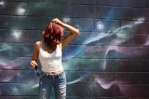 Redheaded woman standing against a painted mural